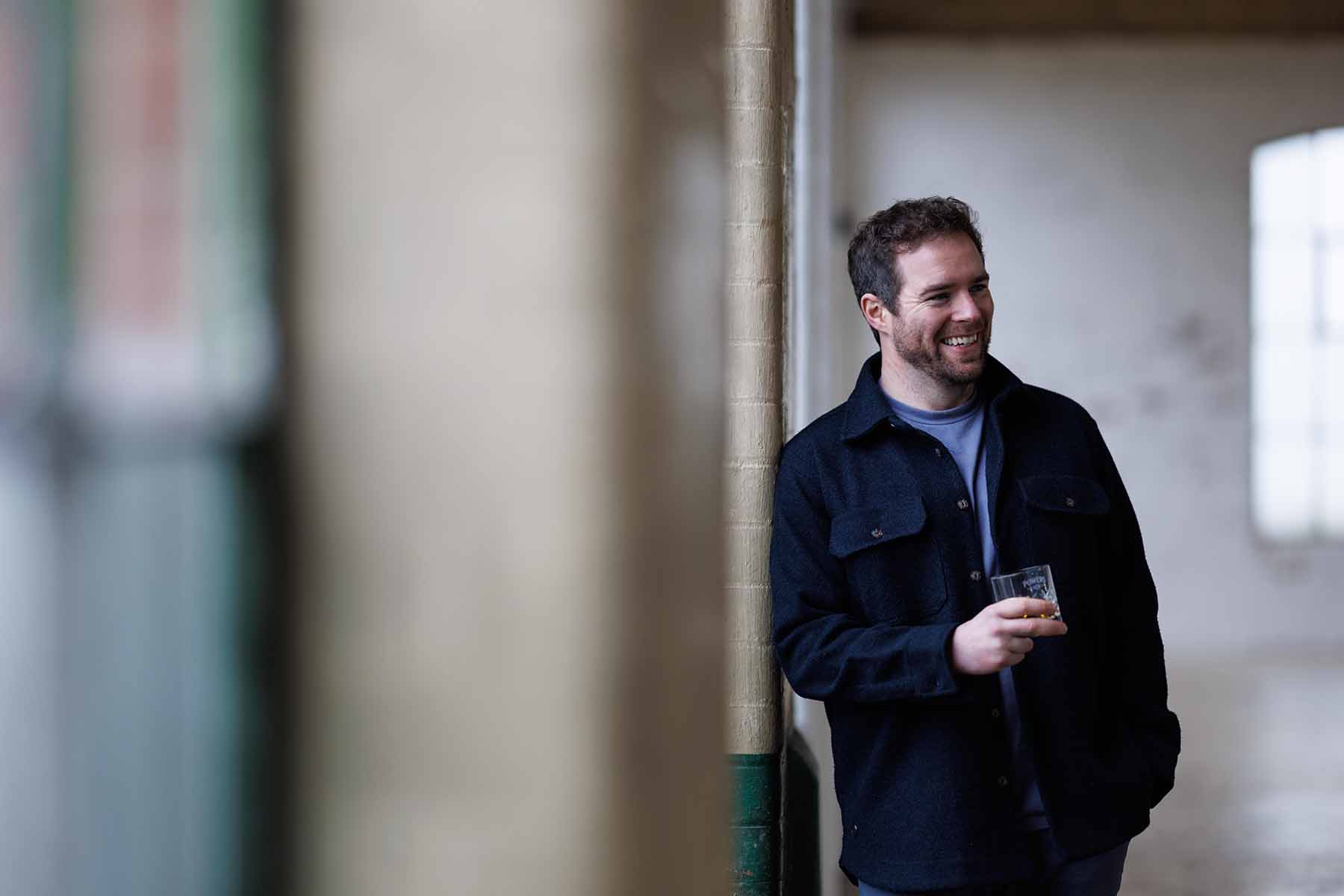 An Image of Ronan Collins Standing with a whiskey glass in hand